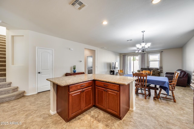 kitchen featuring a center island, decorative light fixtures, a notable chandelier, light stone counters, and light tile patterned floors