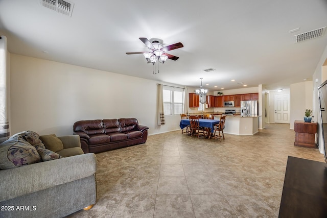 living room with light tile patterned flooring and ceiling fan with notable chandelier