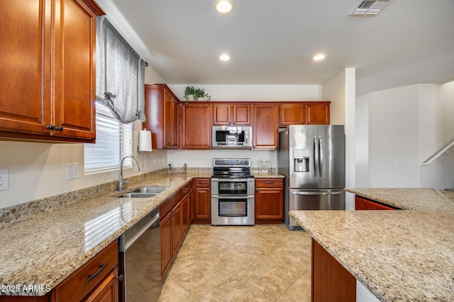 kitchen with sink, light stone counters, light tile patterned floors, and appliances with stainless steel finishes