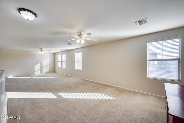 empty room featuring ceiling fan, plenty of natural light, and light carpet