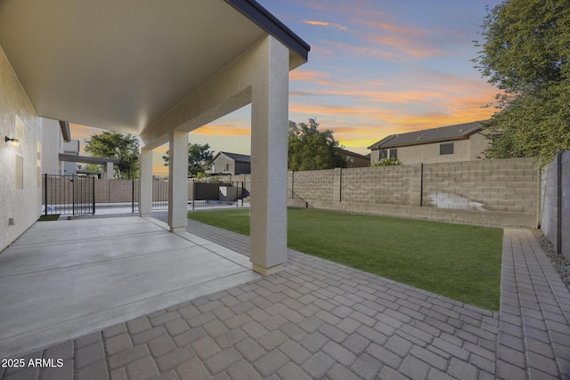 patio terrace at dusk featuring a lawn