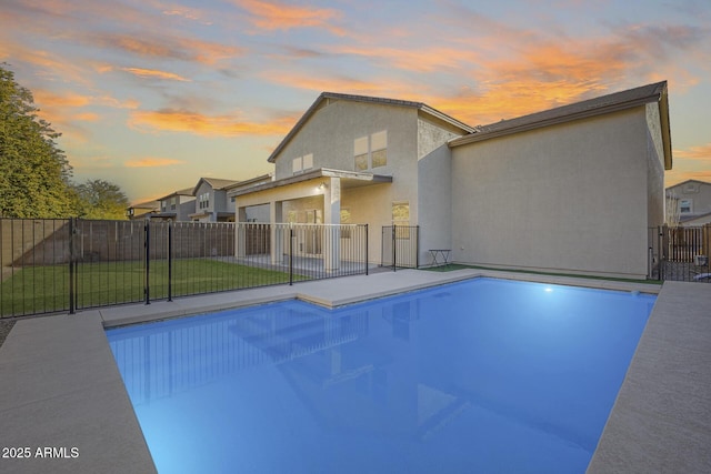 pool at dusk featuring a lawn