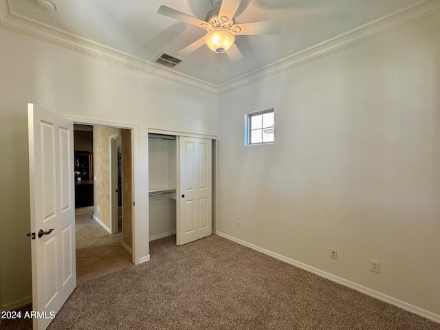 unfurnished bedroom with ornamental molding, a closet, carpet, and ceiling fan