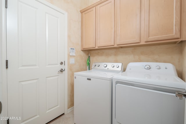 laundry room featuring washer and clothes dryer, light tile patterned flooring, and cabinets