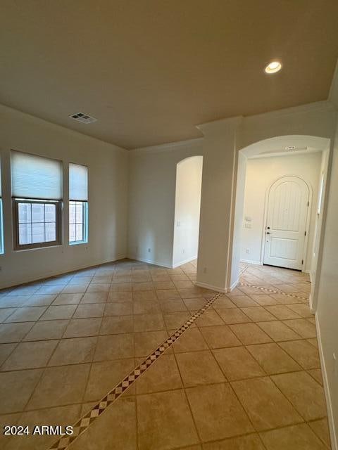 empty room with ornamental molding and light tile patterned floors