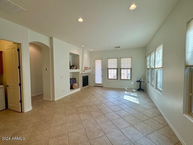 unfurnished living room with built in shelves, washer / clothes dryer, and light tile patterned floors