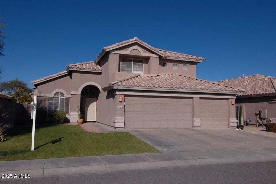 mediterranean / spanish home featuring an attached garage, a tiled roof, concrete driveway, stucco siding, and a front yard