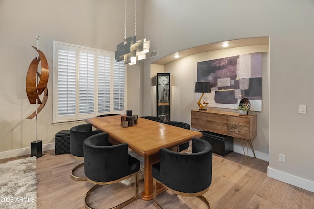 8447 W Tether Trl, Peoria, AZ 85383 - dining room featuring wood finished floors, arched walkways, and a towering ceiling