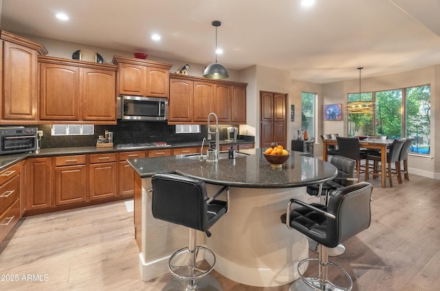 8447 W Tether Trl, Peoria, AZ 85383 - kitchen featuring appliances with stainless steel finishes, brown cabinetry, light wood finished floors, tasteful backsplash, and recessed lighting