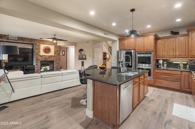 8447 W Tether Trl, Peoria, AZ 85383 - kitchen featuring open floor plan, appliances with stainless steel finishes, light wood-type flooring, a center island with sink, and ceiling fan