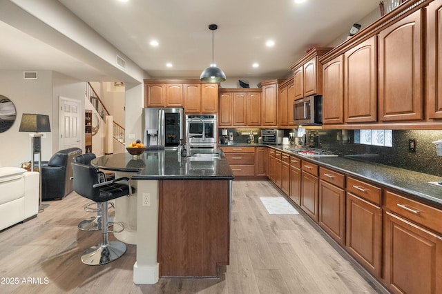 8447 W Tether Trl, Peoria, AZ 85383 - kitchen with appliances with stainless steel finishes, open floor plan, a breakfast bar, light wood-style floors, and an island with sink