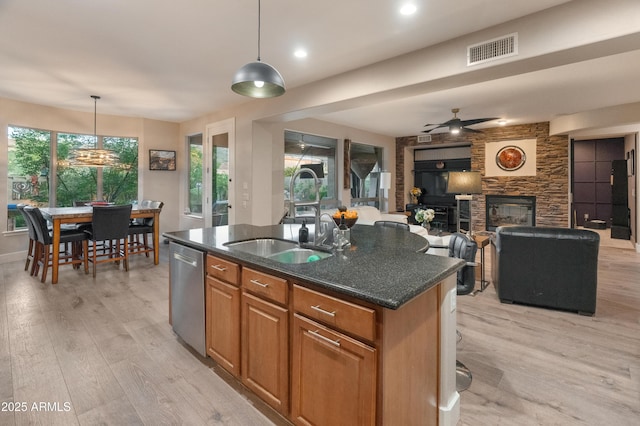 8447 W Tether Trl, Peoria, AZ 85383 - kitchen featuring stainless steel dishwasher, light wood-style flooring, a fireplace, open floor plan, and a center island with sink