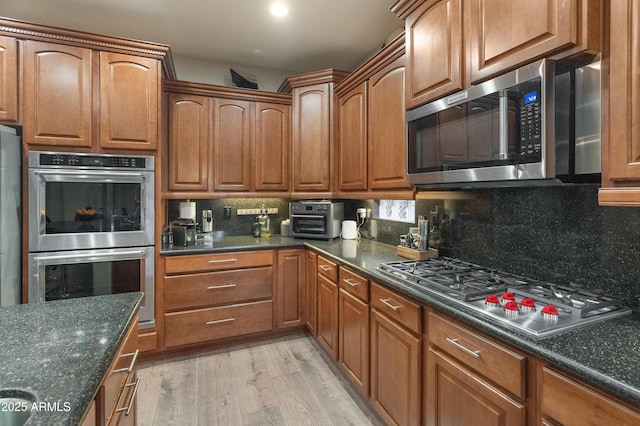 8447 W Tether Trl, Peoria, AZ 85383 - kitchen featuring appliances with stainless steel finishes, light wood-style floors, tasteful backsplash, and brown cabinetry