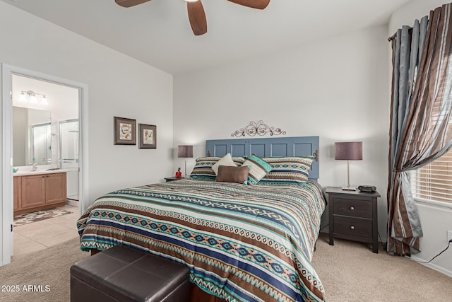 bedroom featuring ceiling fan, light colored carpet, and ensuite bath