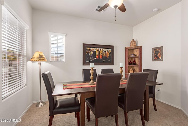 dining area with ceiling fan and light colored carpet