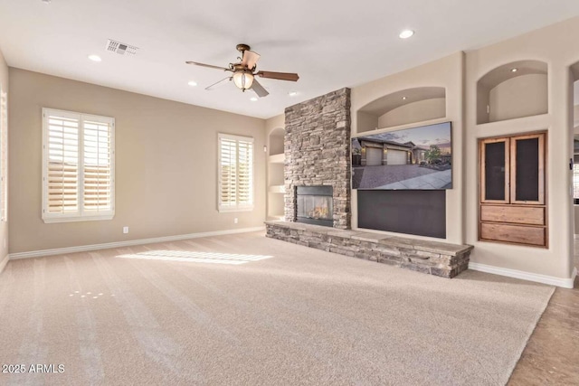 unfurnished living room with ceiling fan, carpet, a fireplace, and plenty of natural light