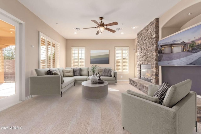 carpeted living room with ceiling fan and a fireplace