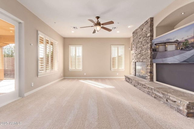 unfurnished living room featuring ceiling fan, carpet, and a stone fireplace