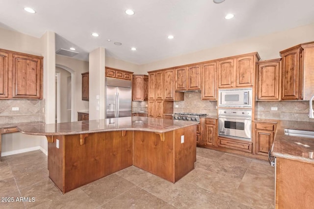 kitchen with a kitchen bar, a center island, and built in appliances