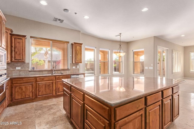 kitchen featuring a kitchen island, tasteful backsplash, sink, hanging light fixtures, and built in microwave