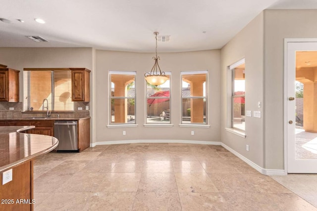 kitchen featuring a wealth of natural light, stainless steel dishwasher, hanging light fixtures, and sink