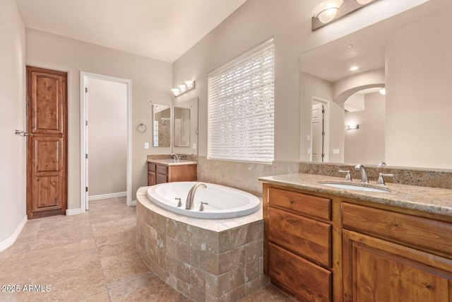 bathroom with vanity and tiled tub