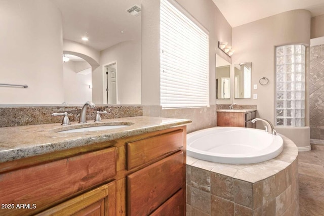 bathroom with tiled bath and vanity