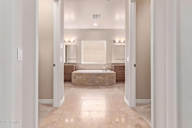 bathroom with tiled bath and vanity