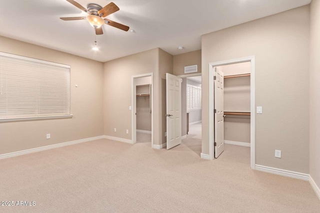 unfurnished bedroom with ceiling fan, a walk in closet, and light carpet