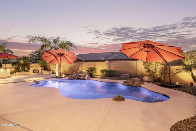 pool at dusk with a patio area