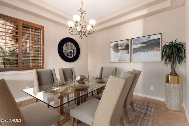 tiled dining space featuring a tray ceiling and an inviting chandelier