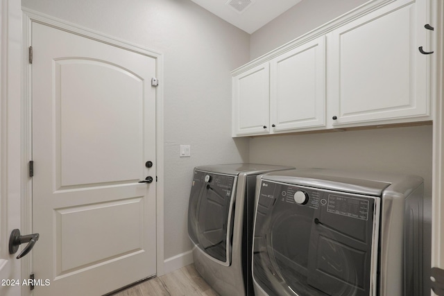 laundry room featuring cabinets, independent washer and dryer, and light hardwood / wood-style flooring