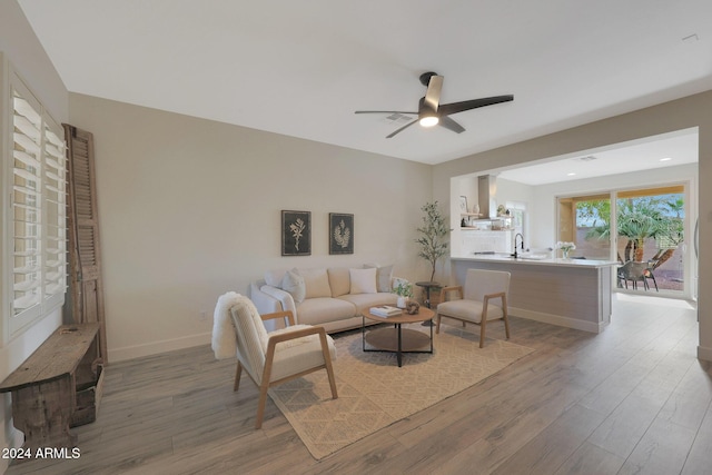 living room with light hardwood / wood-style flooring, ceiling fan, and sink