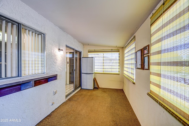 hallway featuring light colored carpet and lofted ceiling