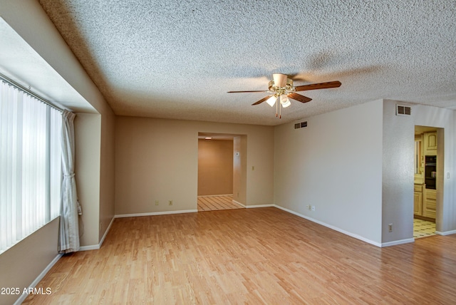 spare room featuring ceiling fan, a textured ceiling, and light wood-type flooring