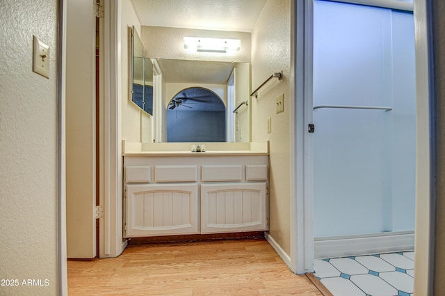 bathroom featuring vanity, a shower with shower door, and wood-type flooring