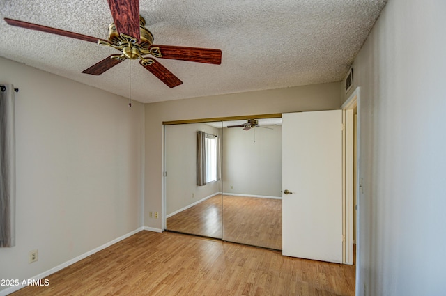 unfurnished bedroom with a textured ceiling, light wood-type flooring, a closet, and ceiling fan