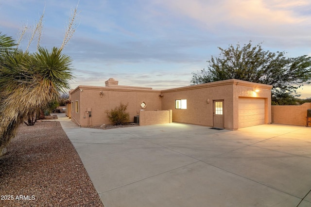 view of side of property with driveway, an attached garage, fence, and stucco siding