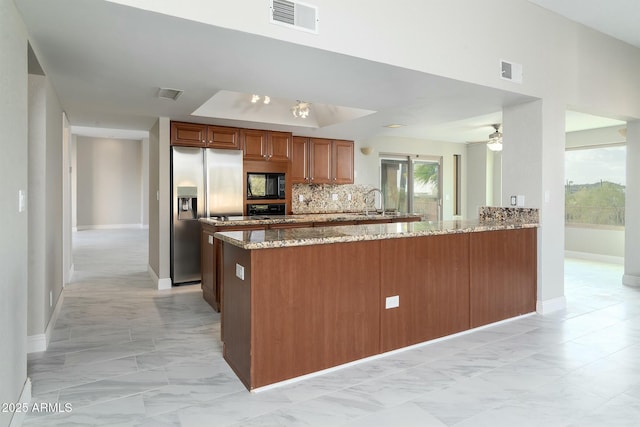 kitchen with stainless steel refrigerator with ice dispenser, visible vents, light stone countertops, black microwave, and a peninsula