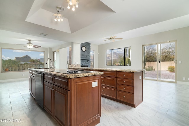 kitchen with black electric stovetop, a sink, dishwasher, a tray ceiling, and an island with sink