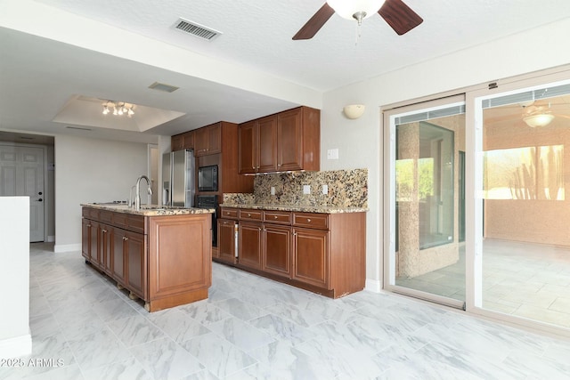 kitchen with light stone counters, visible vents, backsplash, black microwave, and stainless steel fridge with ice dispenser