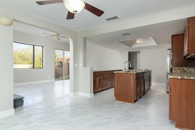 kitchen featuring light stone counters, a sink, visible vents, baseboards, and open floor plan