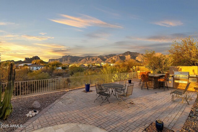 view of patio / terrace featuring outdoor dining space, area for grilling, fence, and a mountain view