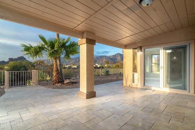 view of patio with a mountain view and fence