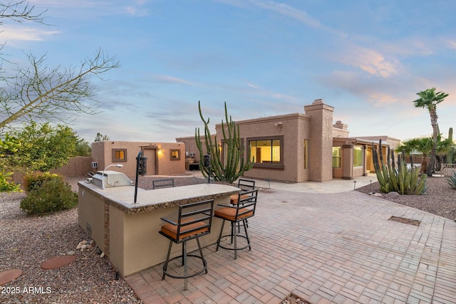 view of patio with an outdoor kitchen, fence, outdoor wet bar, and a grill