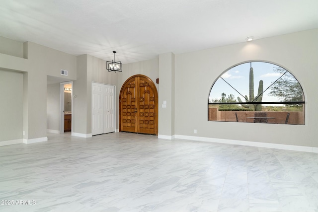 empty room with marble finish floor, visible vents, a chandelier, and baseboards