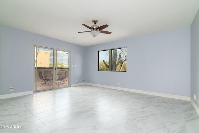 spare room featuring a ceiling fan and baseboards