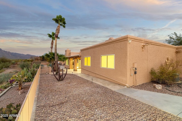 view of home's exterior with a patio area, fence, a mountain view, and stucco siding