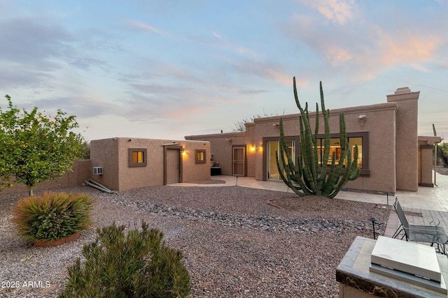 rear view of house featuring a patio area, fence, and stucco siding