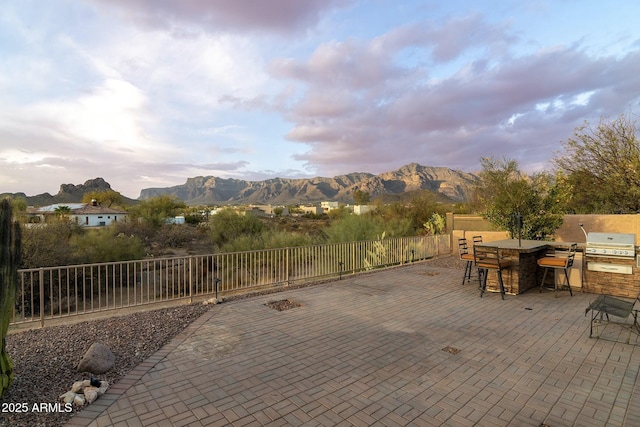 view of patio with a fenced backyard, a grill, a mountain view, and exterior kitchen